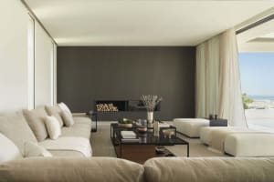Modern living room with minimalist furniture, fabric upholstery, and a fire feature with wood logs.