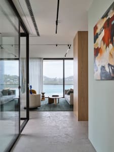 Modern interior design featuring a living room with concrete flooring, glass walls, and an ocean view.
