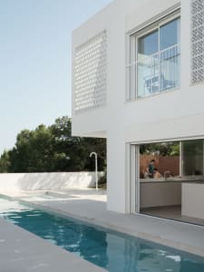 A modern residential space featuring a white stone floor and large windows.