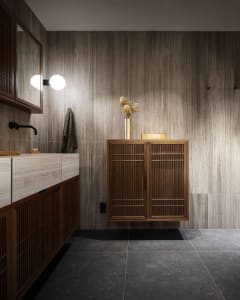 A modern bathroom with wooden cabinets and marble tiles.