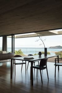 Modern dining room with a glass wall overlooking the ocean.