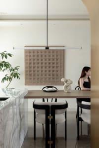 A modern dining room featuring a marble and wood table with leather upholstered chairs, a minimalist sculpture, and a pattern