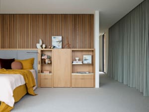 Modern bedroom featuring wooden paneling, fabric headboard, metal shelves, and glass elements.