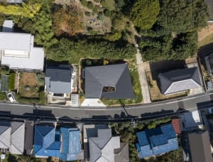 An aerial view of a modern residential roof surrounded by trees and foliage.