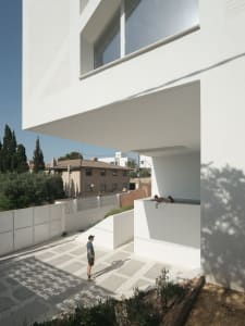A modern, white-rendered residential architecture with an open patio and a swimming pool.