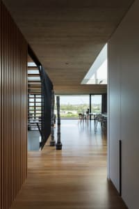 Modern minimalist home interior featuring wooden floors, glass windows, and steel accents