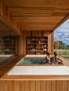 Two people relaxing in a wooden hot tub room