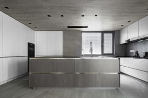 Minimalist kitchen with gray and white color scheme and concrete countertops.