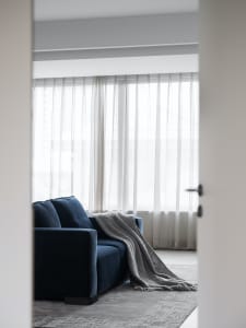 A minimalist living room with a blue sofa, gray throw blanket, and textured cushions.