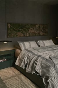 A modern bedroom with gray textiles and a concrete floor.