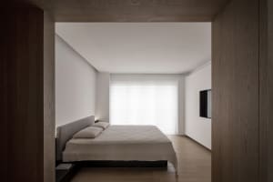 Modern minimalist bedroom with a wood floor and white walls.