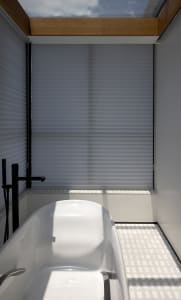 Modern bathroom with white tiles, glass shower enclosure, and freestanding tub.