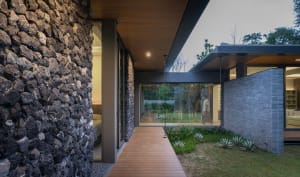 Modern minimalist exterior design featuring stone cladding, glass walls, and wooden accents.
