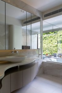 A modern marble bathroom with a floating vanity and large window overlooking greenery.