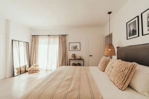 A minimalist bedroom featuring light-colored bedding and woven fabric elements.
