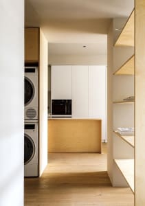A minimalist kitchen with wood and laminate flooring, featuring white cabinets and a wooden island.