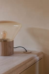 A modern lamp with a transparent glass shade placed on a desk.