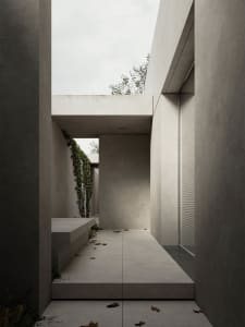 A minimalist interior space featuring concrete walls and floor, with a skylight providing natural light.