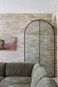 Modern living room featuring brick walls, a gray couch, and a framed painting.