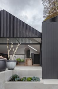 A modern minimalist house with a concrete exterior, featuring a geometric design and an overhanging roof.