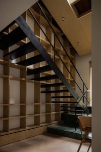 Modern minimalist interior design featuring a black metal stairway with wooden shelves and marble elements.
