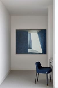 A minimalist office space featuring a large blue painting on the wall with a geometric design.