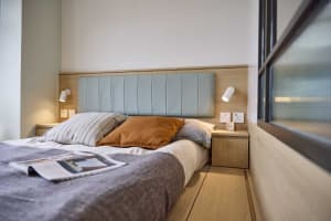 A modern bedroom featuring a wooden headboard with blue accents, soft lighting, and a cozy atmosphere.