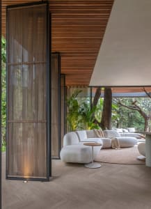 Modern interior design featuring a sleek, curved white sofa in a living room setting with a wooden floor, ceiling, and white 