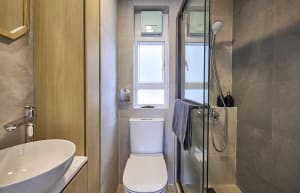 A modern minimalist bathroom with white oval sink, white toilet, and ceramic tiles. Features include a window, glass shower e