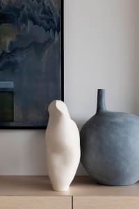 Two ceramic vases with abstract shapes placed on a wooden surface.