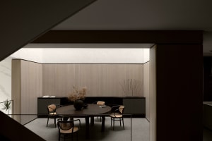 Modern minimalist dining room featuring wooden furniture and a round table with chairs.