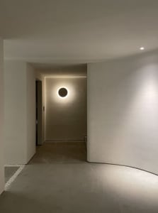 Modern hallway with minimalist design featuring a circular light fixture and concrete floor.