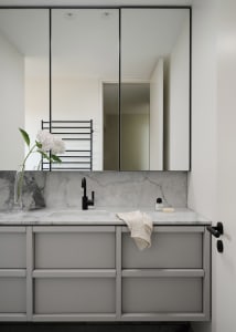Minimalist modern bathroom with marble countertop and sink, black fixtures, and grey cabinets.