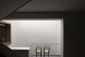 Two minimalist chairs in a modern, minimalist concrete interior space.