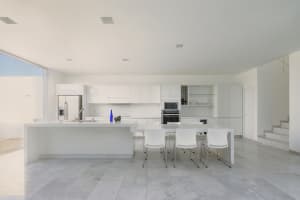 Modern residential kitchen with white marble flooring and countertops.