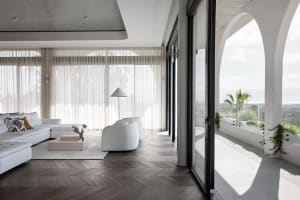 A modern living room with white furniture and large windows showcasing a terrace.