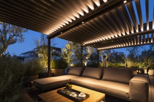 Outdoor living space with modern furniture and wood pergola at dusk.