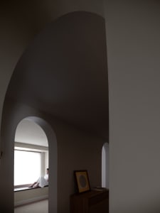 A minimalist interior space with concrete walls and a large window.