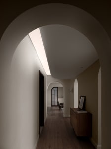 A minimalist hallway with arched doorways and warm, neutral colors.