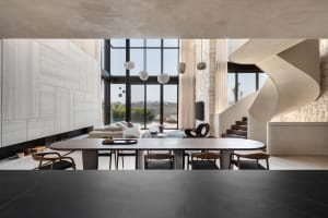 Modern living room with concrete walls, glass windows, and metal furniture.