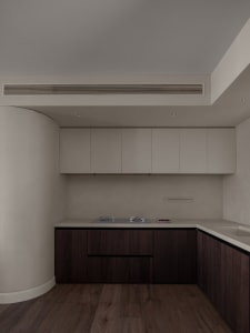 Modern kitchen featuring white cabinets and wooden flooring with a stainless steel stove and white countertops.