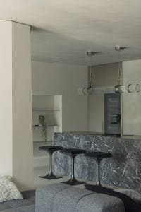 A modern living room with a marble counter and sleek, black stools.