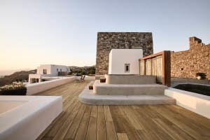 A modern residential patio featuring concrete structures, stone walls, and wooden flooring.
