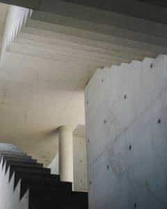A modern industrial interior space with concrete walls and ceiling.