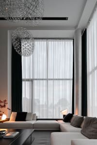 Modern living room featuring textured curtains, minimalist furniture, and contemporary lighting.