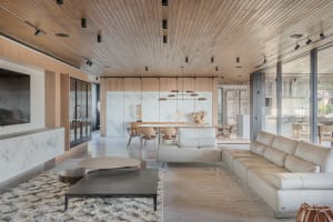 A modern living room with wooden ceiling, marble walls, and a leather sofa.