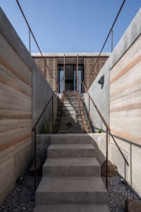 Concrete steps with wooden railings leading up to a modern building entrance.