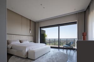 A modern bedroom with a large bed, white bedding, and neutral-colored furniture in a contemporary living space.