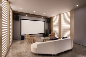 A modern home theater interior with a white screen, beige armchairs, and a white sofa.