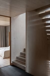 A modern minimalist staircase built from wooden steps and walls.